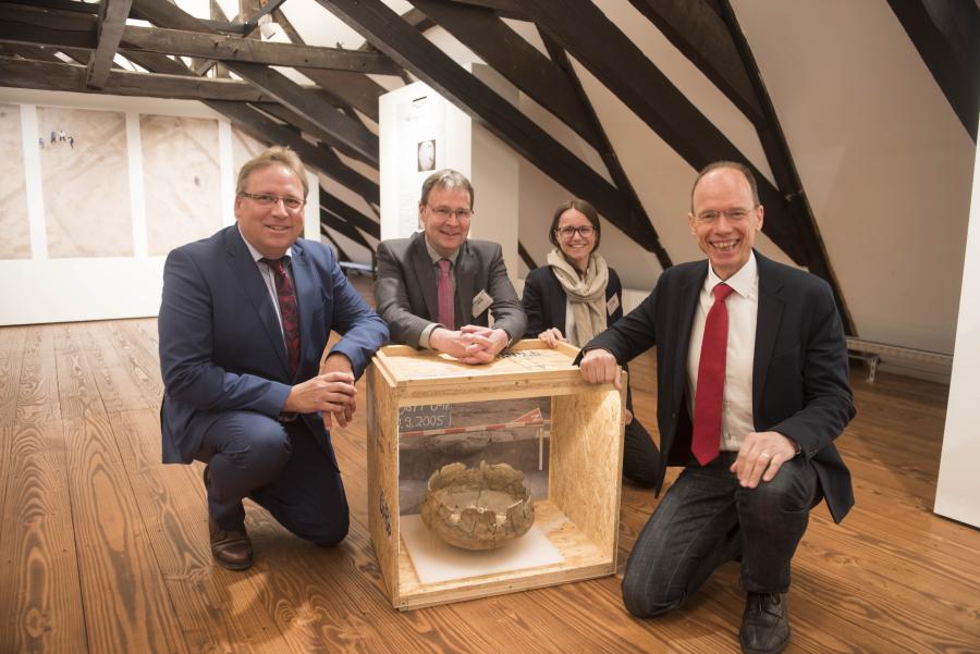 "Vorsicht Urne": Bersenbrücks Samtgemeindebürgermeister Horst Baier (links) und Landrat Michael Lübbersmann (rechts) begutachten gemeinsam mit Axel Friederichs, Leiter der Stadt- und Kreisarchäologie, und Judith Franzen, Stadt- und Kreisarchäologie und Kuratorin der Ausstellung, vorsichtig ein Objekt der Ausstellung.