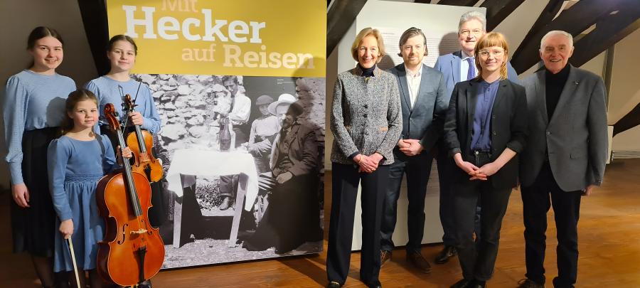 Die Musikerinnen Chiara, Mariella und Leonie Wolf, Kuratorin Ulrike Hamm, Sebastian Hohdorf (Direktor Amtsgericht Bersenbrück), Kreisrat Matthias Selle, Claudia Stuckenberg (Museum im Kloster) und Franz Buitmann (Kreisheimatbund Bersenbrück) eröffneten gemeinsam die neue Sonderausstellung „Mit Hecker auf Reisen“. Foto: Landkreis Osnabrück/Ulrich Eckseler