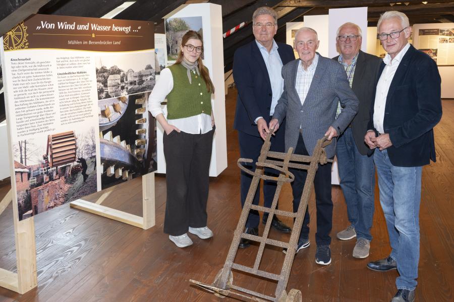 Vor der Ausstellung im Dachgeschoss des Museums im Klosters sieht man von links Museumsleitung Kim Winkelmann, Kreisrat Matthias Selle, Franz Buitmann (Vorsitzender des Kreisheimatbundes Bersenbrück), Bernd Zur-Lienen (Besitzer und Betreiber der Hasemühle) und Bürgermeister der Stadt Bersenbrück Christian Klütsch. Franz Buitmann hält außerdem eine alte Sackkarre in den Händen. Im Hintergrund sieht man die Ausstellungstafeln und Stationen der Sonderausstellung.