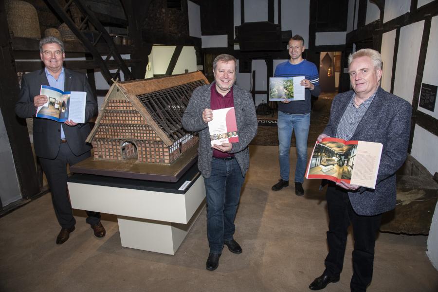 Präsentierten am Gebäudemodell des Bauernhofs „Wehlburg“ das Buch „Kloster, Amtssitz, Kreismuseum. Das Museum im Kloster Bersenbrück“ (von links): Kreisrat Matthias Selle, Autor Arnold Beuke, Fotograf Uwe Lewandowski sowie der Leiter des Kulturbüros, Burkhard Fromme Foto: Landkreis Osnabrück/Hermann Pentermann