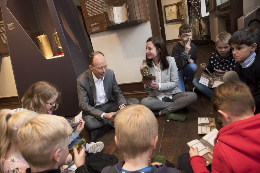 Landrat Michael Lübbersmann und Sabrina Sommerfeld vom Kulturbüro des Landkreises Osnabrück testen mit Kindern aus dem Altkreis Bersenbrück das neue Kinderheft. Foto: Landkreis Osnabrück / Uwe Lewandowski